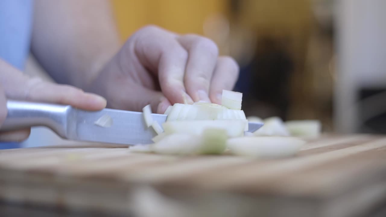 Static shot of a man with no skill chopping onions