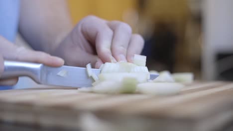 static shot of a man with no skill chopping onions