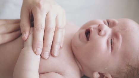 newborn boy with fair hair cries lying on changing table