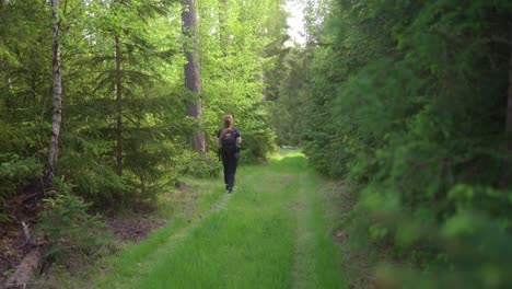 Girl-with-a-backpack-travels-through-the-green-forest