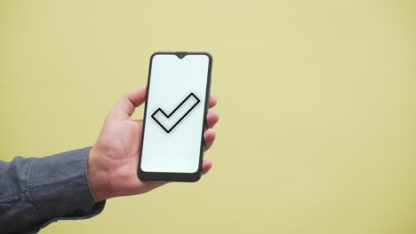 una mano muestra una marca de verificación aprobada en un teléfono inteligente