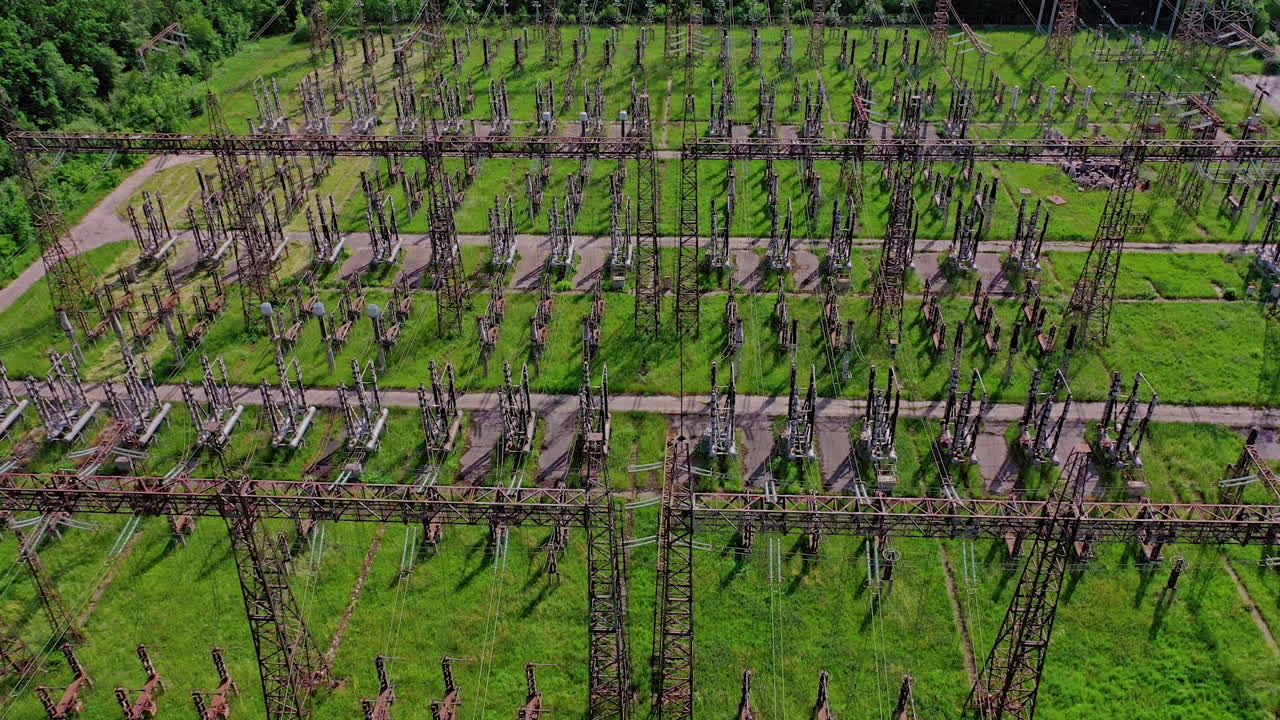 Electric supports among green field.Flight over huge field with high voltage steel pylons. High voltage lines in nature. Aerial view.
