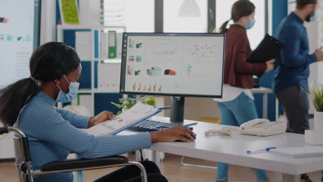 black woman with disabilities and protection face masks working on computer