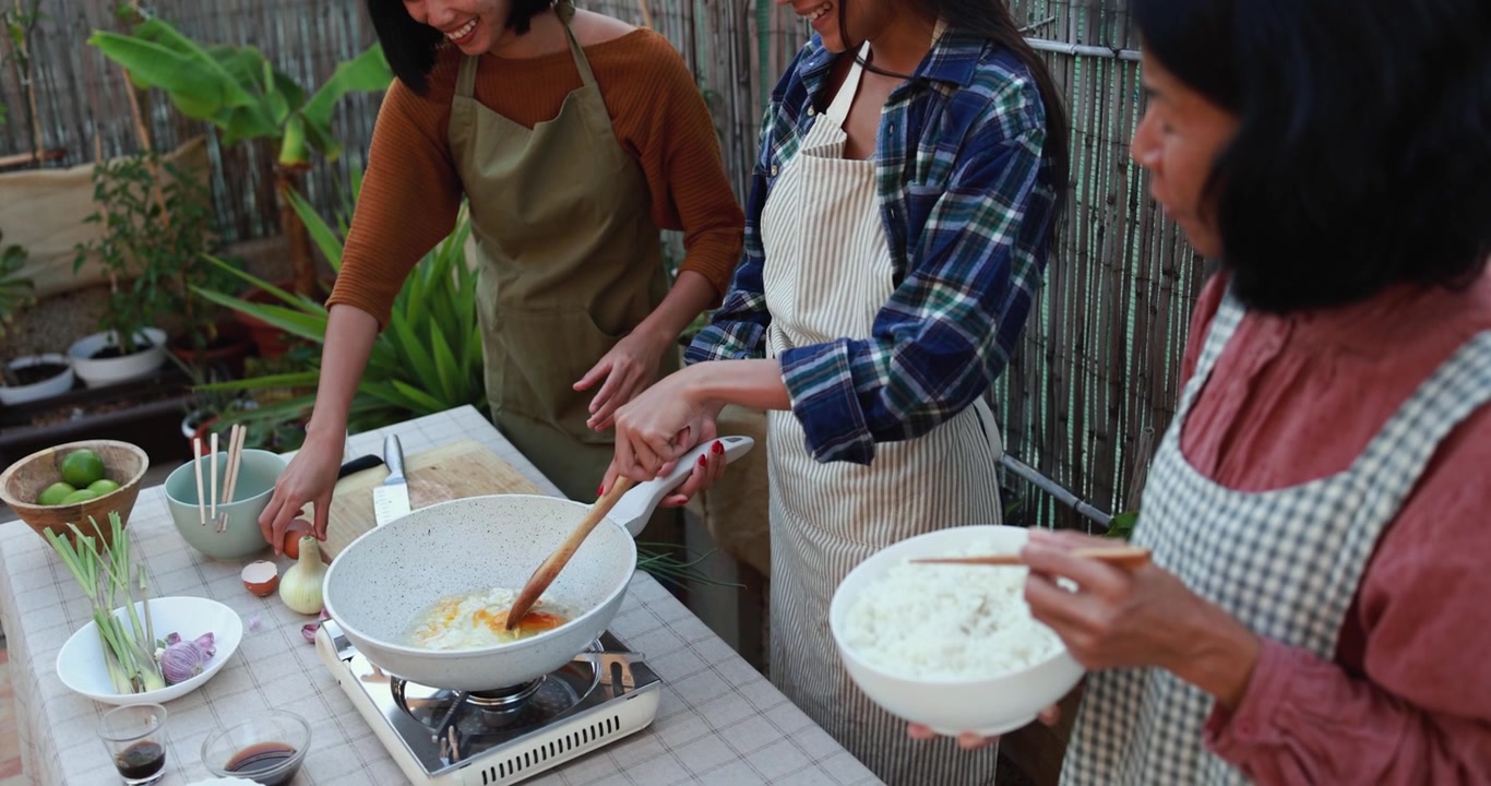 屋外キッチンで一緒に料理する3人のアジア人女性
