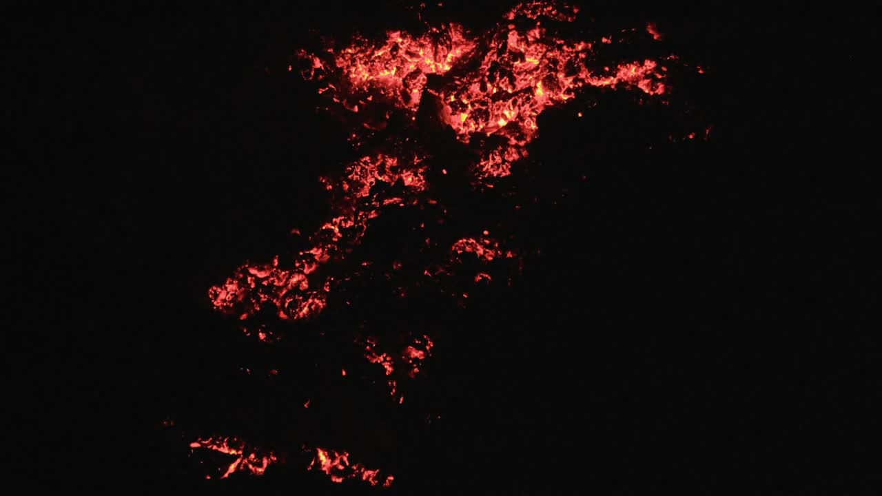 rocas de lava iluminadas por una linterna en la oscuridad, revelando el brillante resplandor rojo de la lava derretida y la textura de las rocas volcánicas circundantes