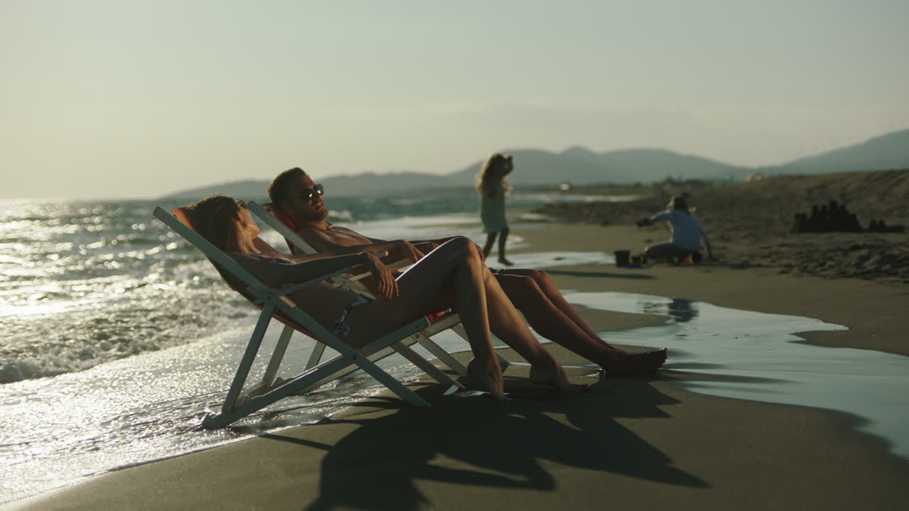 una pareja relajándose en la playa al atardecer.