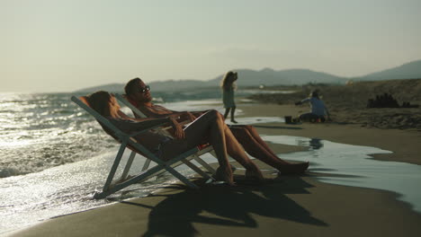 couple relaxing on beach at sunset