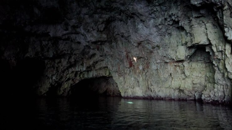 Mysterious atmosphere inside a sea cave with a beam of light reflecting on water and projecting against a rocky wall, Vis island, Adriatic Sea, Croatia