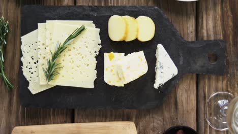 variety of cheese, olives, biscuits and rosemary herbs on wooden table