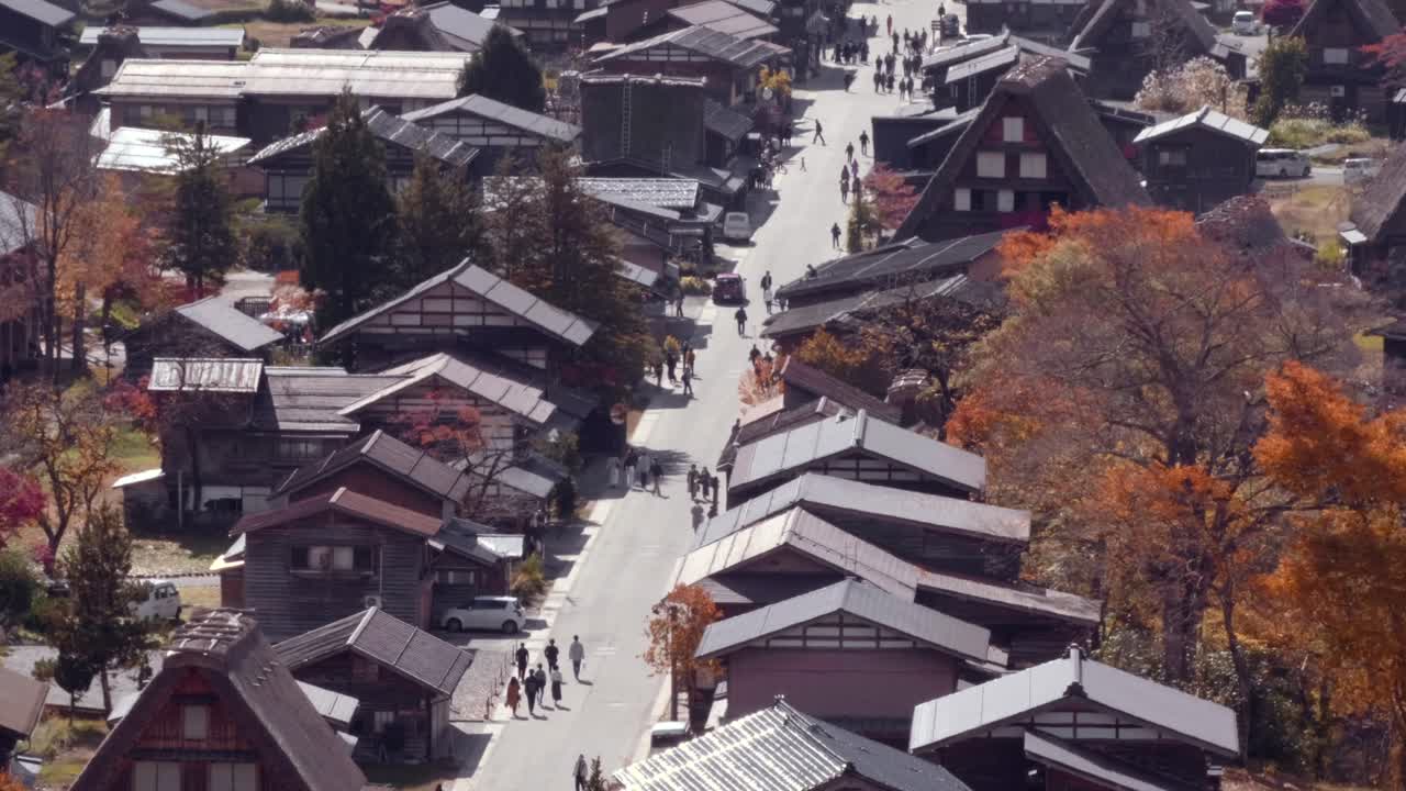 una vista de teleobjetivo de personas caminando por las calles del casco antiguo de shirakawago en japón durante el otoño