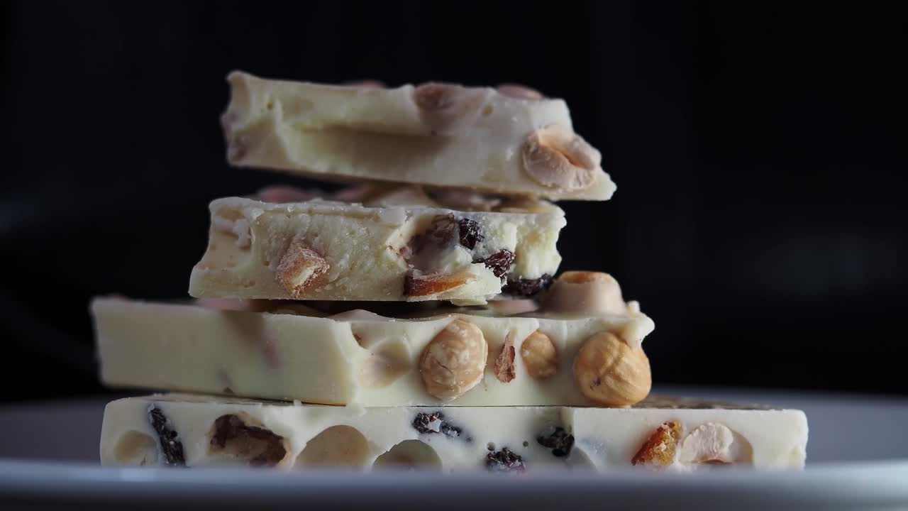 Hand Picking Up a Piece of White Chocolate with Nuts and Dried Fruits