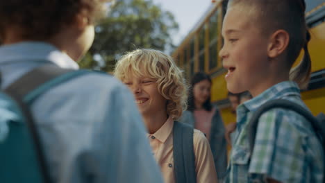 preteen schoolboys stand laughing at bus. boys wait for schoolbus boarding.