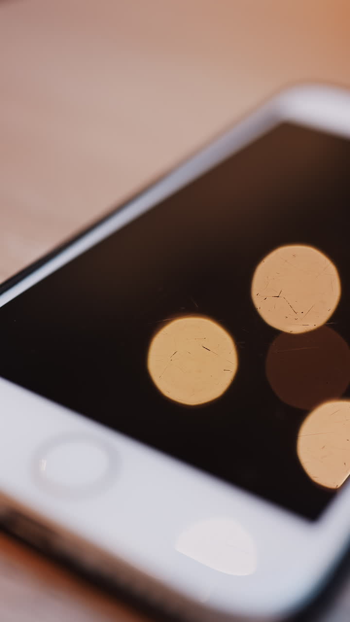 Close up of lights reflected on a phone screen. Vertical