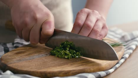 close up of hands of woman cutting chives at the kitchen.