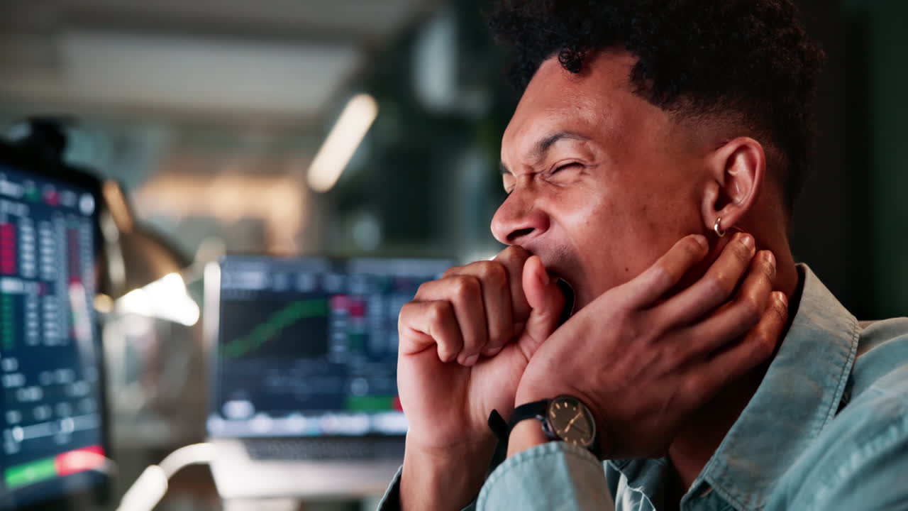 un hombre de negocios cansado bostezando en su computadora.