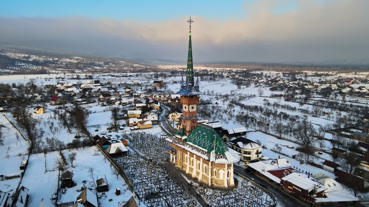 Letecký dronový pohled na Veselý hřbitov v Săpânța v zimě, Rumunsko. Mnoho náhrobků, kostel, sníh.