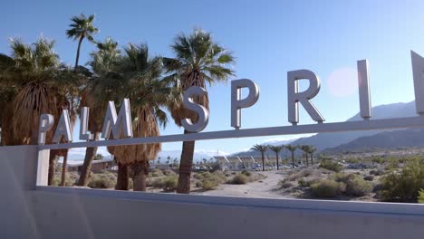 Palm-Springs,-California-welcome-sign-at-city-entrance-with-cars-driving-on-a-sunny-day-with-video-panning-left-to-right