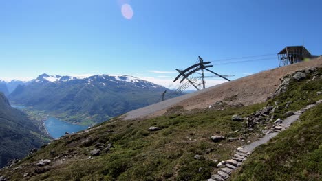 Gondola-lift-descending-from-mountain-Hoven-Norway---Idyllic-static-shot-with-spectacular-landscape-background-and-sheep-grassing-around-top-station