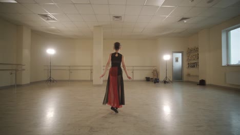 a group of young ballet students in black dancewear practicing positions in a spacious ballet studio with wooden flooring and wall-mounted barres. focused expressions and synchronized movements.