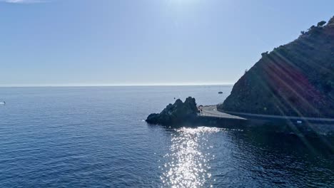 Sunlit Ocean Coastline with Cliff, Road, and Sparkling Water