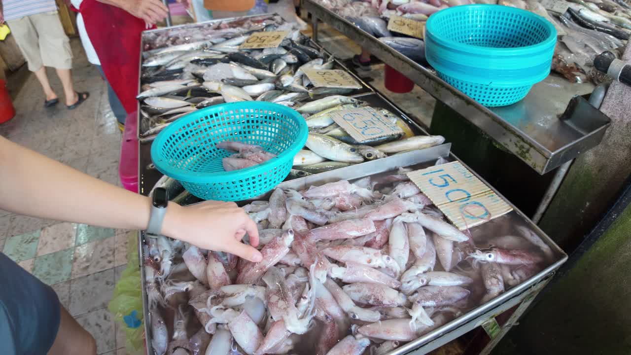 imágenes vibrantes que muestran a diversas personas seleccionando calamares frescos en un bullicioso mercado húmedo, destacando el rico y auténtico estilo de vida local y las opciones tradicionales de mariscos