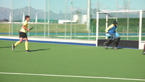 playing field hockey, male players interacting with goalkeeper on field
