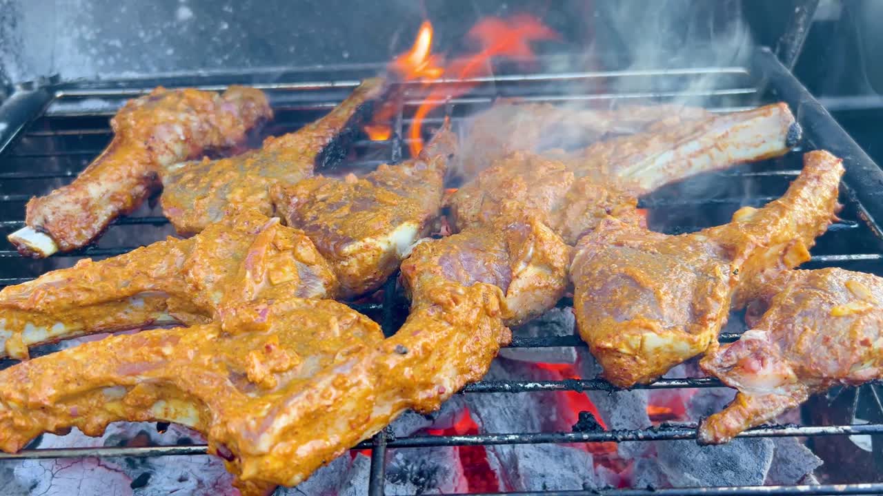 Lamb chops cooking over open flames on grill