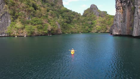 4K-drone-video-of-a-couple-kayaking-around-Big-Lagoon-near-Coron-in-Palawan,-Philippines