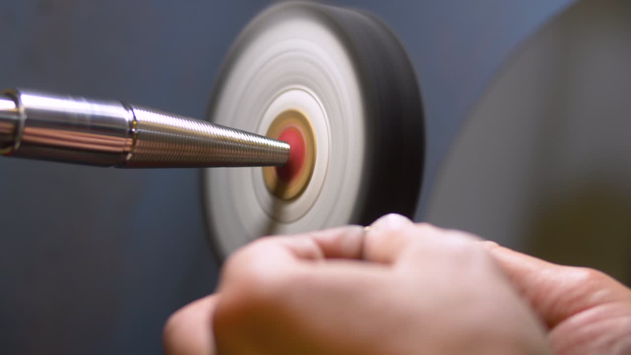 남성 보석 제작자가 보석 제작 워크숍에서 은반지를 연마하고 연마합니다.