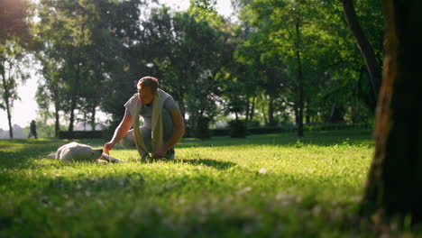 Relaxed-man-petting-golden-retriever.-Playful-dog-chew-leash-lying-on-grass