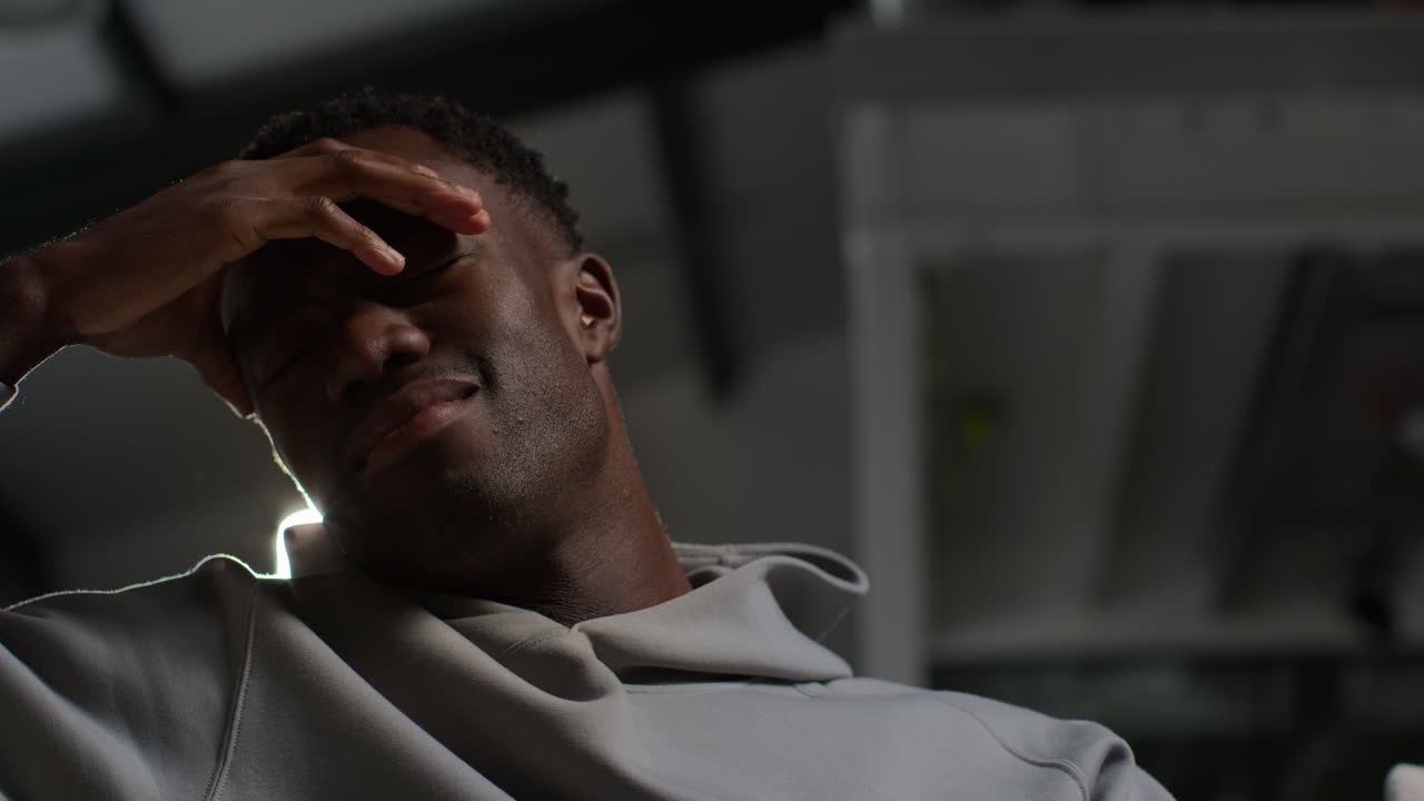 cerca de la iluminación de clave baja disparo de un joven infeliz y deprimido con la cabeza en las manos sacudiendo la cabeza 1