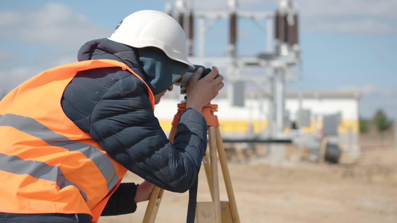 un ingeniero topógrafo toma mediciones en la construcción de una subestación de transformador