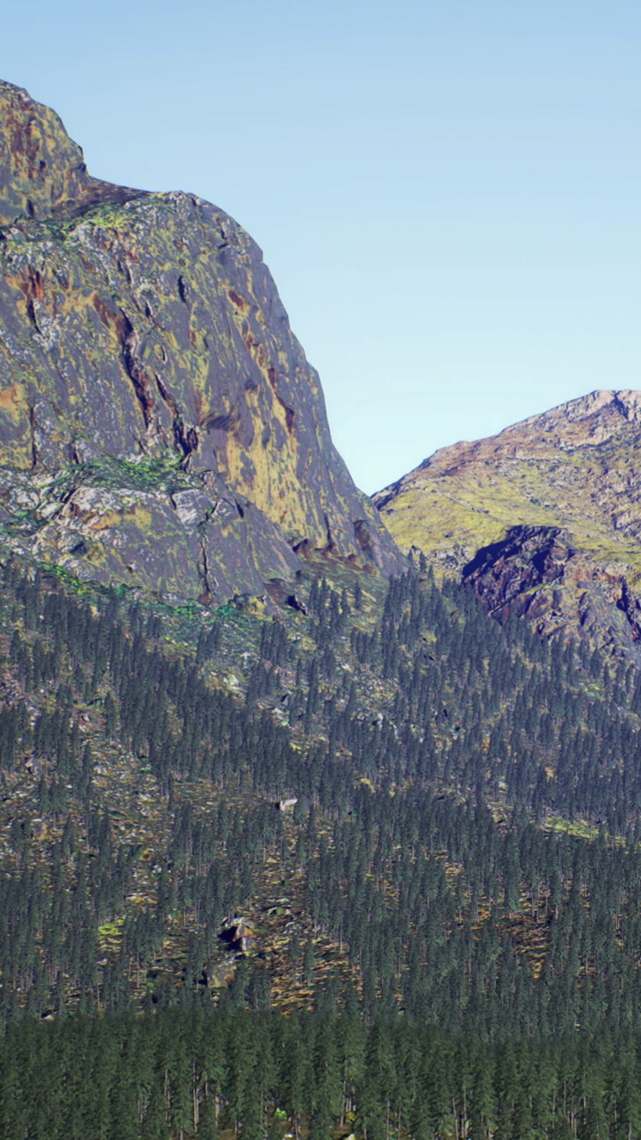 Majestic mountain peak rises above the vibrant forest under clear blue sky