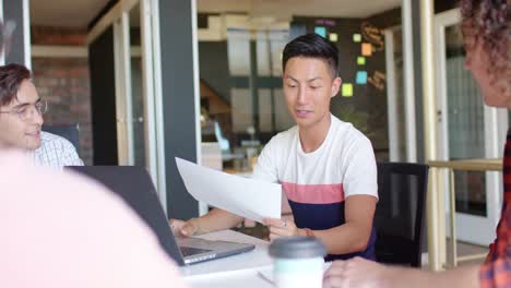 asian businessman discussing work with diverse creative colleagues in casual meeting, slow motion