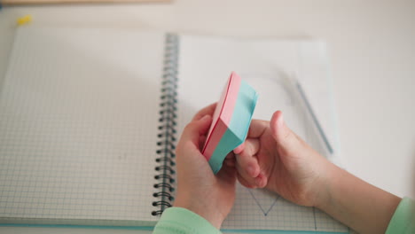 little schoolgirl student flips memo notes over copybook