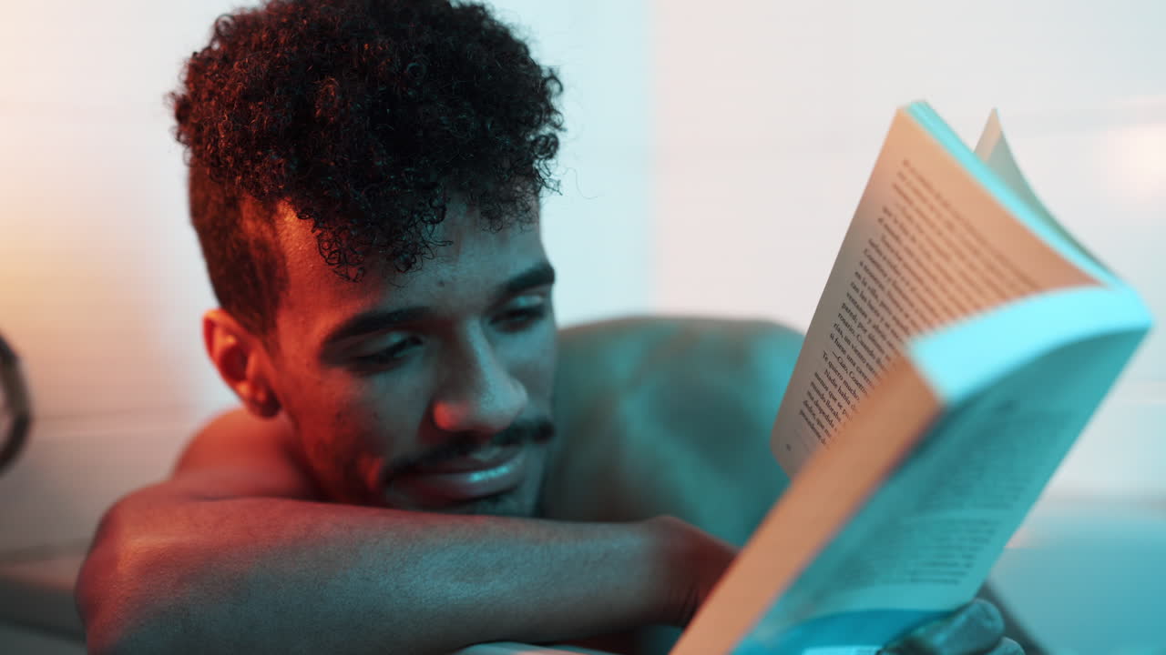 Investing reading books by nude black handsome man in bathtub