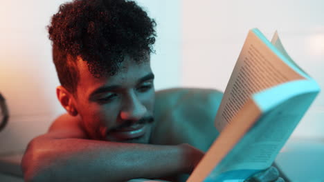 invertir leyendo libros de hombre guapo negro desnudo en la bañera
