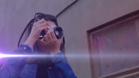 punto de luz contra la fotógrafa caucásica haciendo clic en imágenes con cámara digital al aire libre