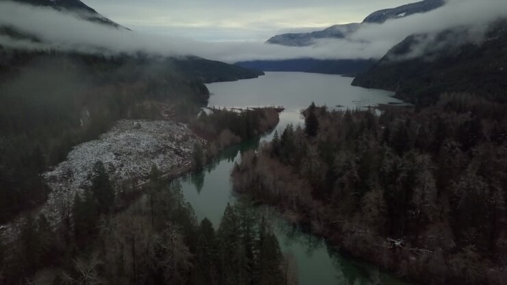 Ripresa aerea inclinata e nuvolosa di una valle invernale con fiume e montagne sull'isola di Vancouver, Canada