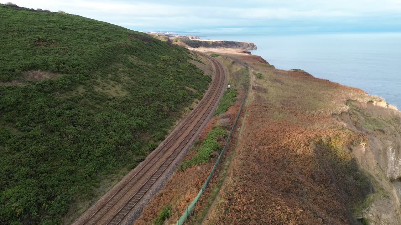 Rising Drone shot of East Coast Railway and cliffs with autumn foliage. County Durham, UK