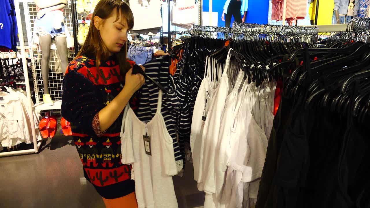 ヨーロッパのアウトレットでショッピング。服を選ぶ少女。セールと割引