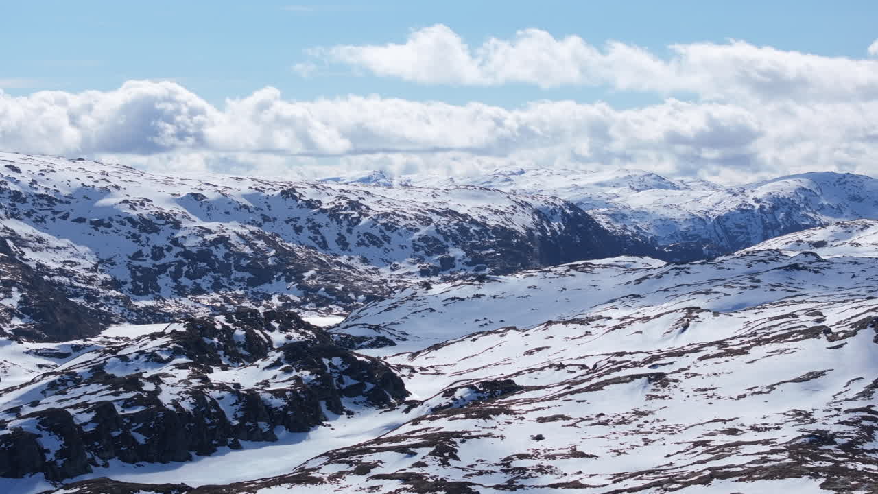 Smooth side-tracking aerial view of Matrefjellene in spring, highlighting rugged peaks with lingering snow