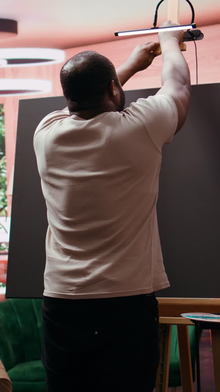 Homem montando tela em branco em cavalete no estúdio de arte.