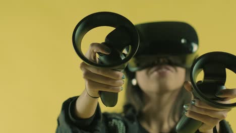 joven jugando con controladores y se pregunta qué tan increíble en el auricular vr. casco de realidad virtual en el fondo amarillo.