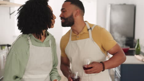 pareja, cocinando y bebiendo vino tinto en la cocina