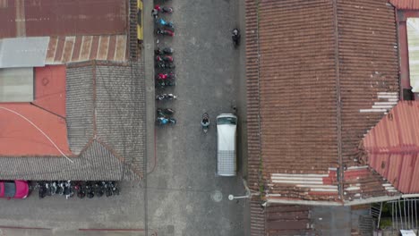 vista aérea siguiendo scooters en las calles de antigua, guatemala - ojo de pájaro, disparo de drones