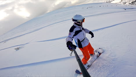 lonely ride by the snowy slope of the mountain. snowboarder takes selfie as he descends.