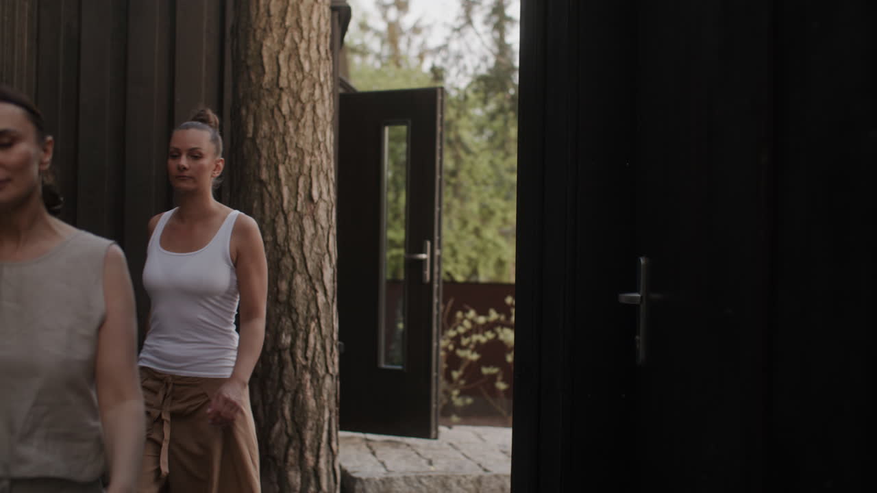 Two Women Walking Through a Modern Wooden Cabin Doorway