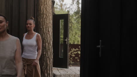 two women walking through a modern wooden cabin doorway