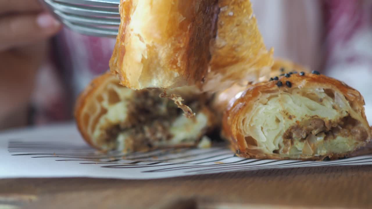 Close-up of a person eating a savory meat-filled pastry